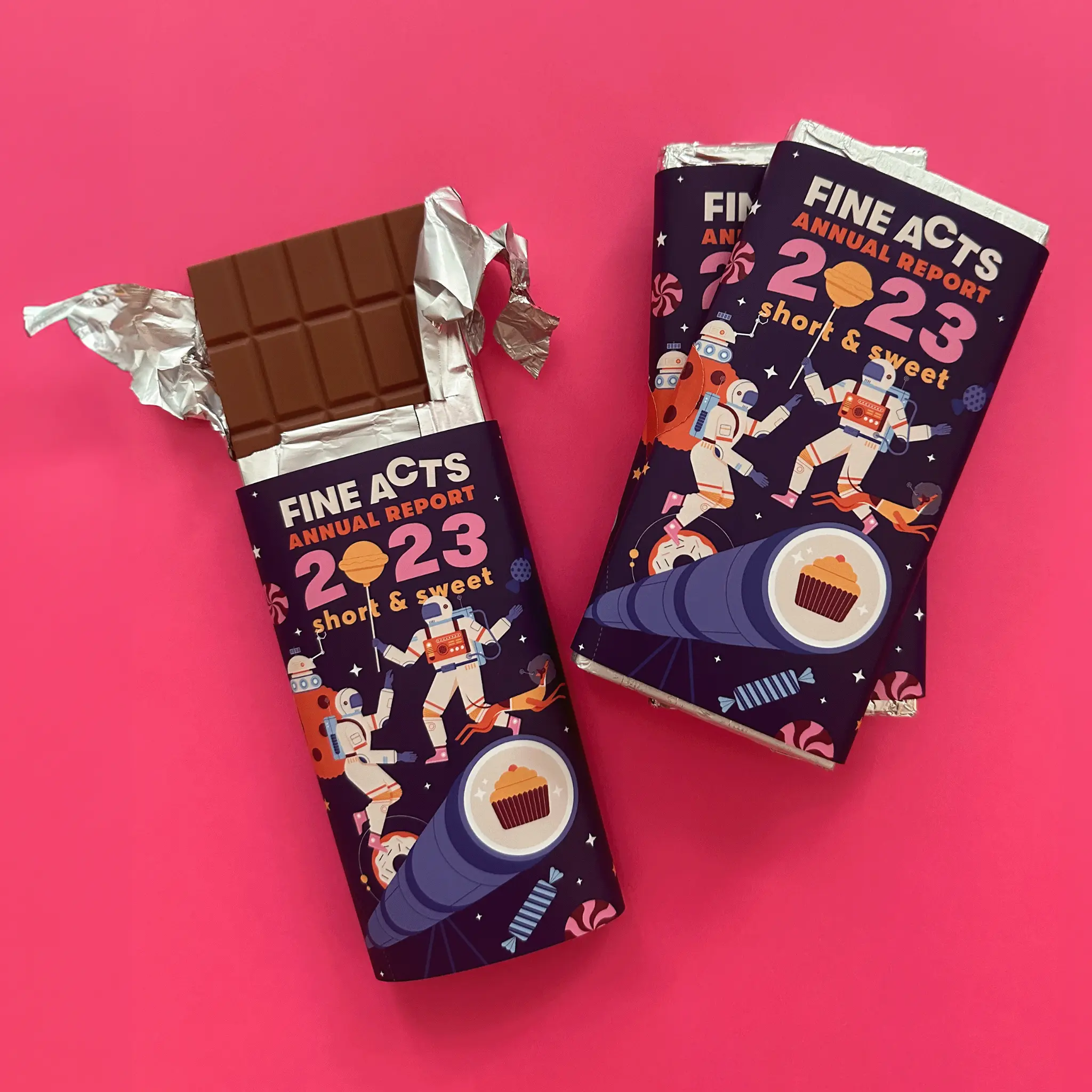 Chocolate bar wrapper designed as the Fine Acts Annual Report 2023 with illustrated astronauts and sweets, shown as a two-sided package.